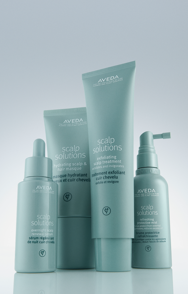 Four teal-colored Aveda Scalp Solutions hair care products, including sprays and creams, are arranged upright with labels facing forward against a light background—perfect for complementing your facials or makeup routine. - Salon Spa Aura in Appleton, WI